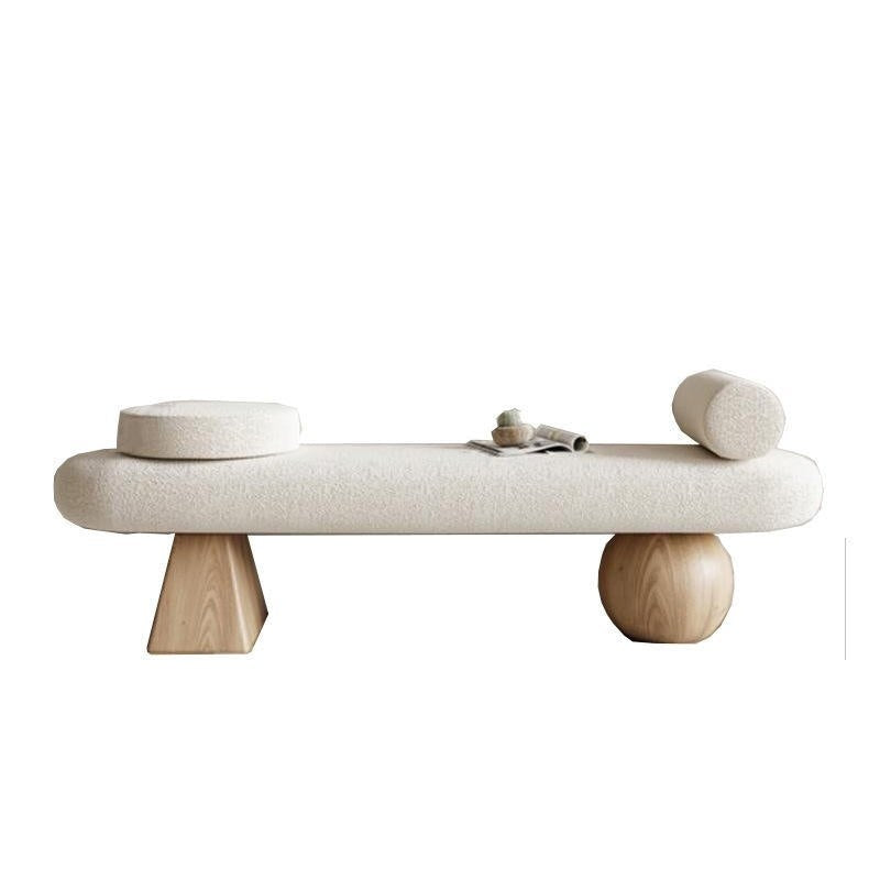 75-inch off-white boucle-upholstered end-of-bed bench with natural wood legs — one tapered geometric leg and one spherical leg — styled with a round bolster, a circular cushion and a small magazine on top.