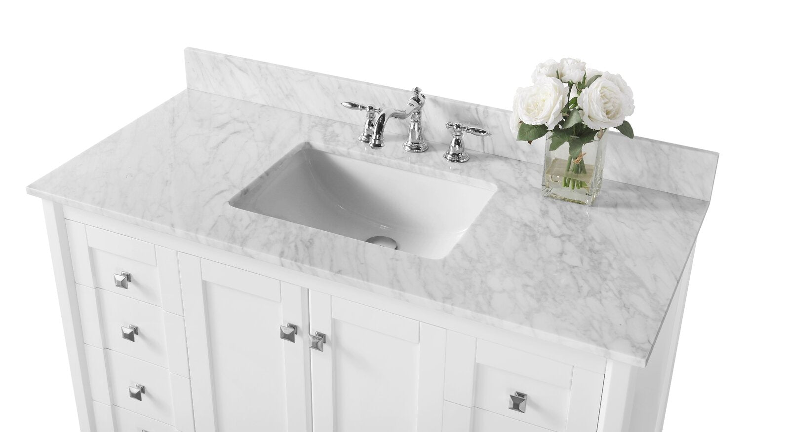 Modern single-sink white solid-wood bathroom vanity with stone marble top and backsplash, rectangular undermount ceramic sink, chrome widespread faucet and square chrome knobs, with a glass vase of white roses at right.