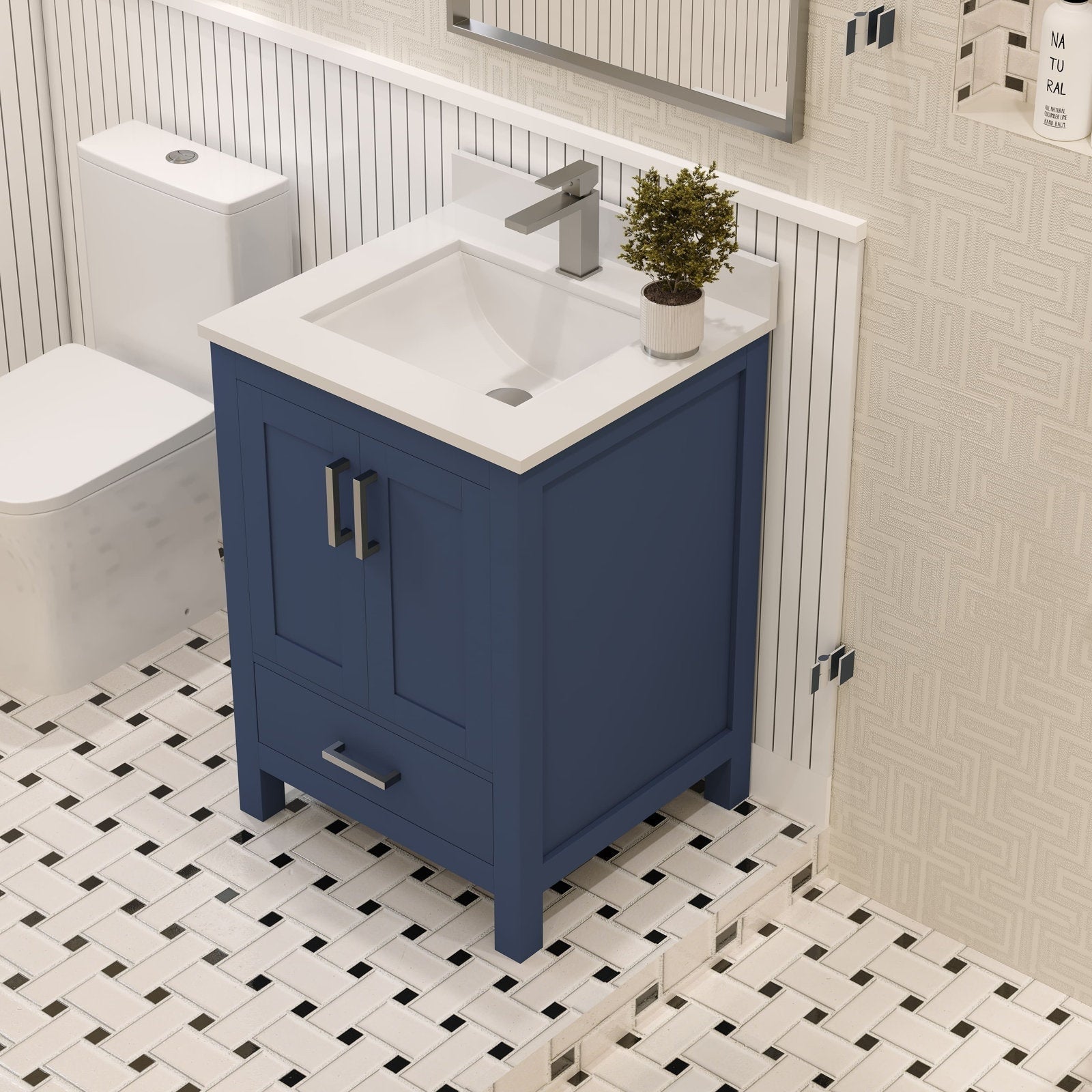 Freestanding 24-inch modern solid wood bathroom vanity with white stone top and integrated ceramic sink, navy blue wooden cabinet with metal handles and single drawer on white-and-black patterned tile next to a toilet.