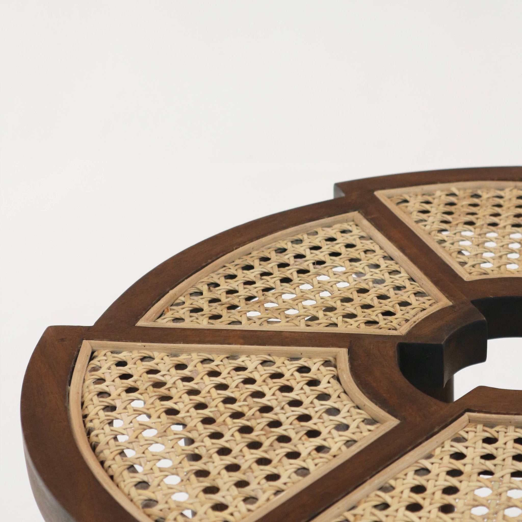 Close-up of a teak brown side table top showing woven natural cane panels set into a solid wood frame with a circular center opening, highlighting mid-century modern rattan-inset detailing.