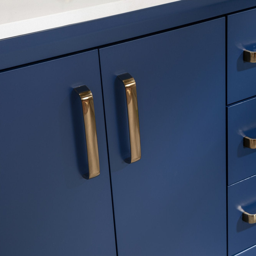 Close-up of a modern navy solid wood vanity with a white stone top, showing polished brass cabinet handles on the center doors and adjacent drawers.