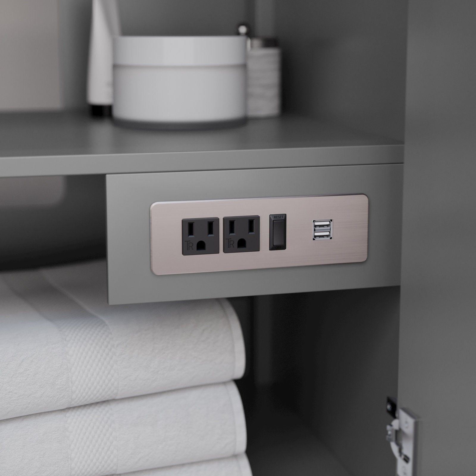 Interior of a stone-colored solid wood modern bathroom vanity showing a built-in brushed-metal outlet panel with two grounded sockets, a reset switch and dual USB ports mounted above folded white towels.