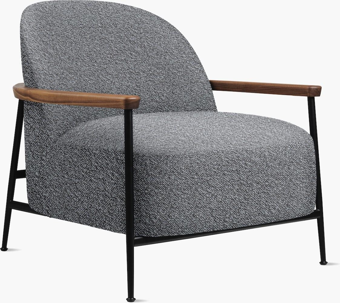 Modern accent lounge chair upholstered in textured grey boucle fabric, featuring curved wooden armrests and a slim black metal frame with tapered legs.