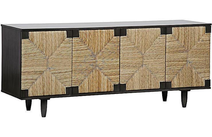 Long coastal sideboard with a dark solid wood frame and four woven seagrass cabinet doors featuring a geometric starburst pattern, raised on tapered legs in natural and black finishes.