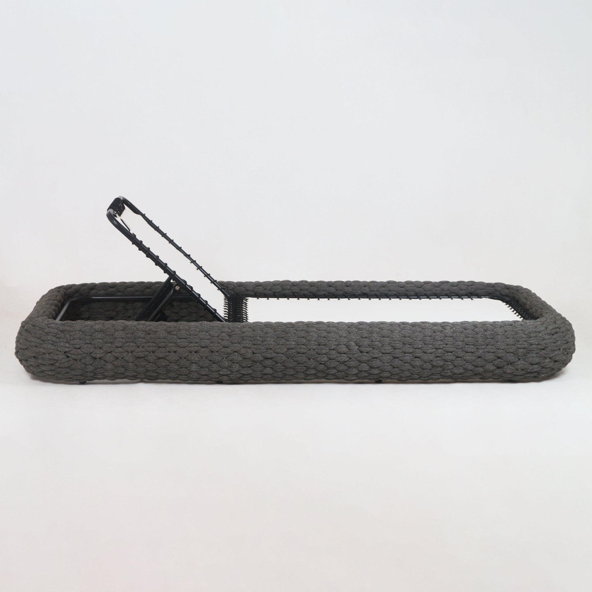 Side view of a taupe rope-woven outdoor chaise lounger with chunky braided rope frame, white fabric sling seat and black metal adjustable backrest partially raised on a white background.
