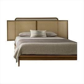 Scandinavian teak platform bed with a three-panel rattan cane headboard, low wooden base and neutral beige bedding with a single accent pillow.