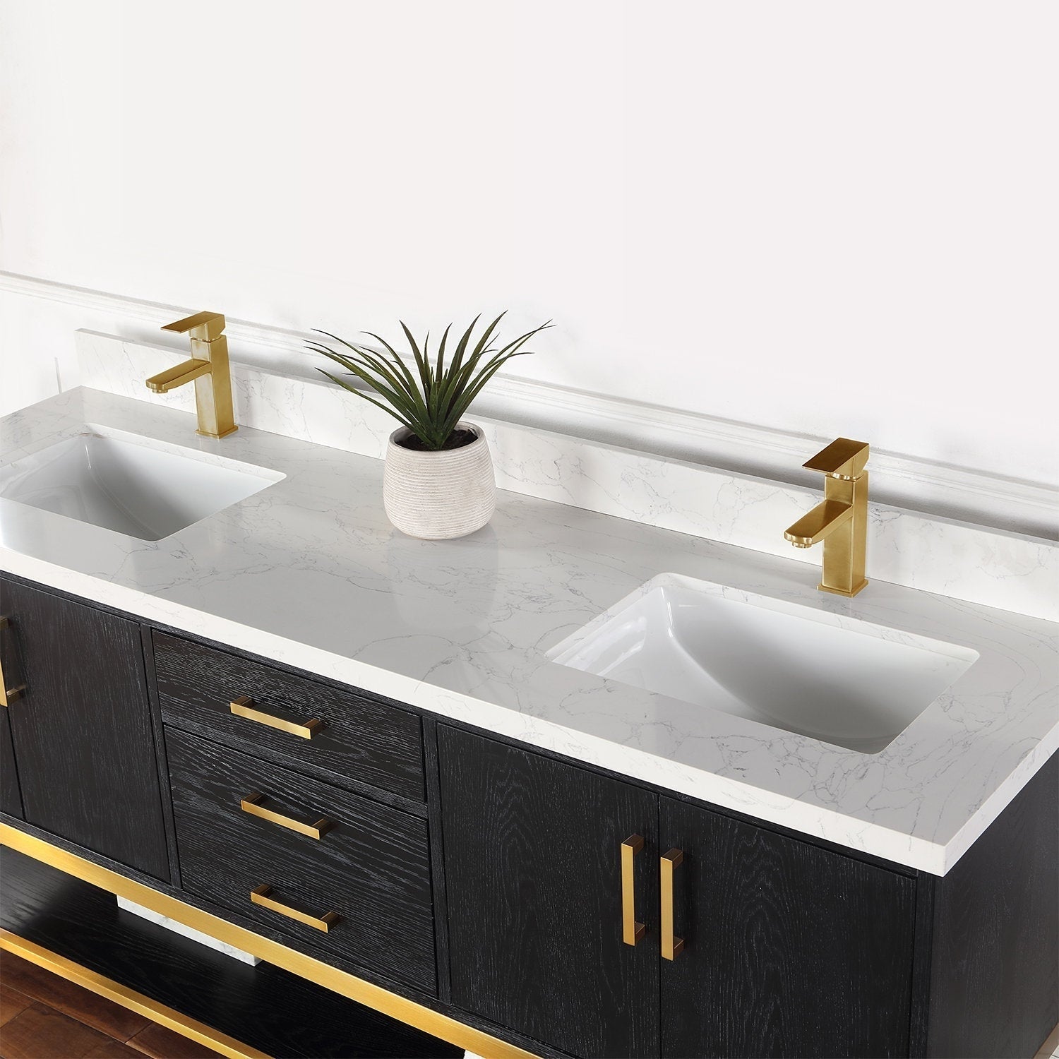 Modern solid wood double-sink bathroom vanity with a stone-look white marble countertop, two rectangular undermount ceramic sinks, brushed gold faucets and matching hardware, and a small potted plant on the counter.
