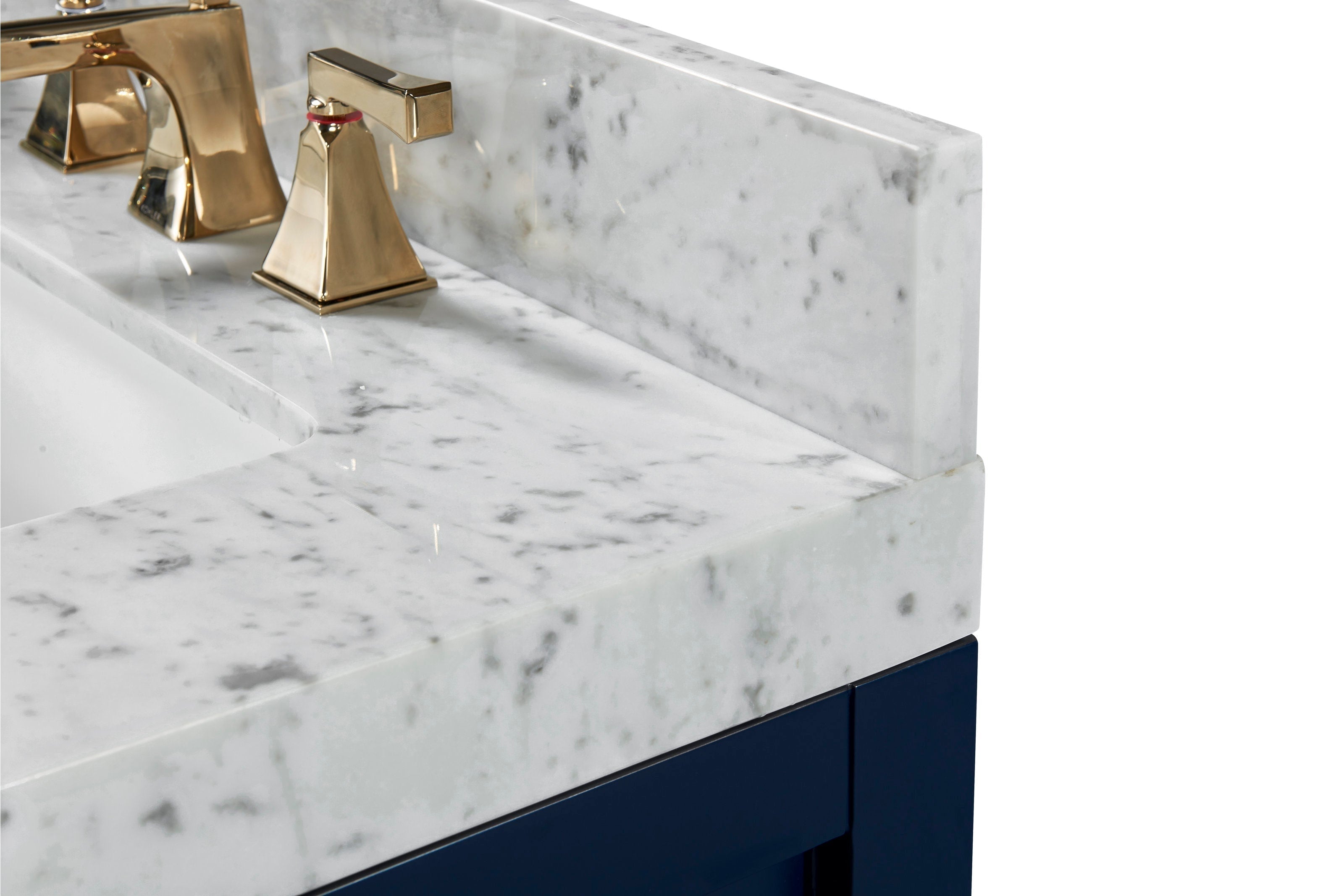 Close-up of a stone marble countertop and backsplash with a white undermount sink, polished brass modern faucet handles, and a navy solid-wood vanity base.