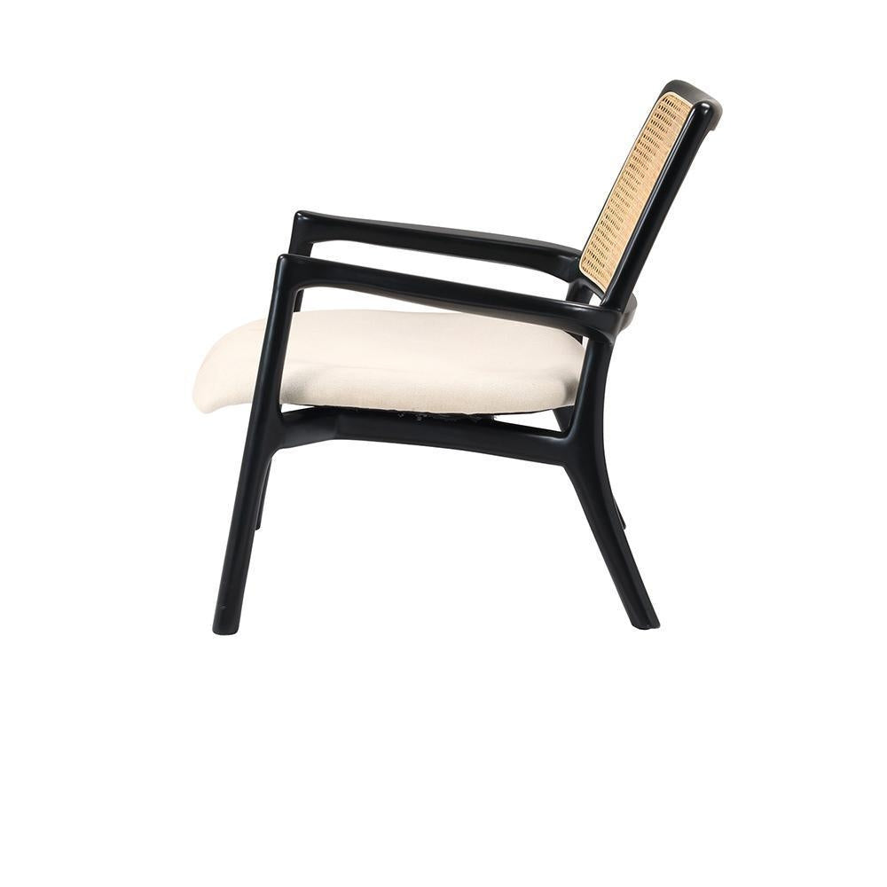 Side view of a modern lounge chair with a mahogany solid wood frame, woven cane backrest and a cream upholstered fabric seat cushion on a white background.