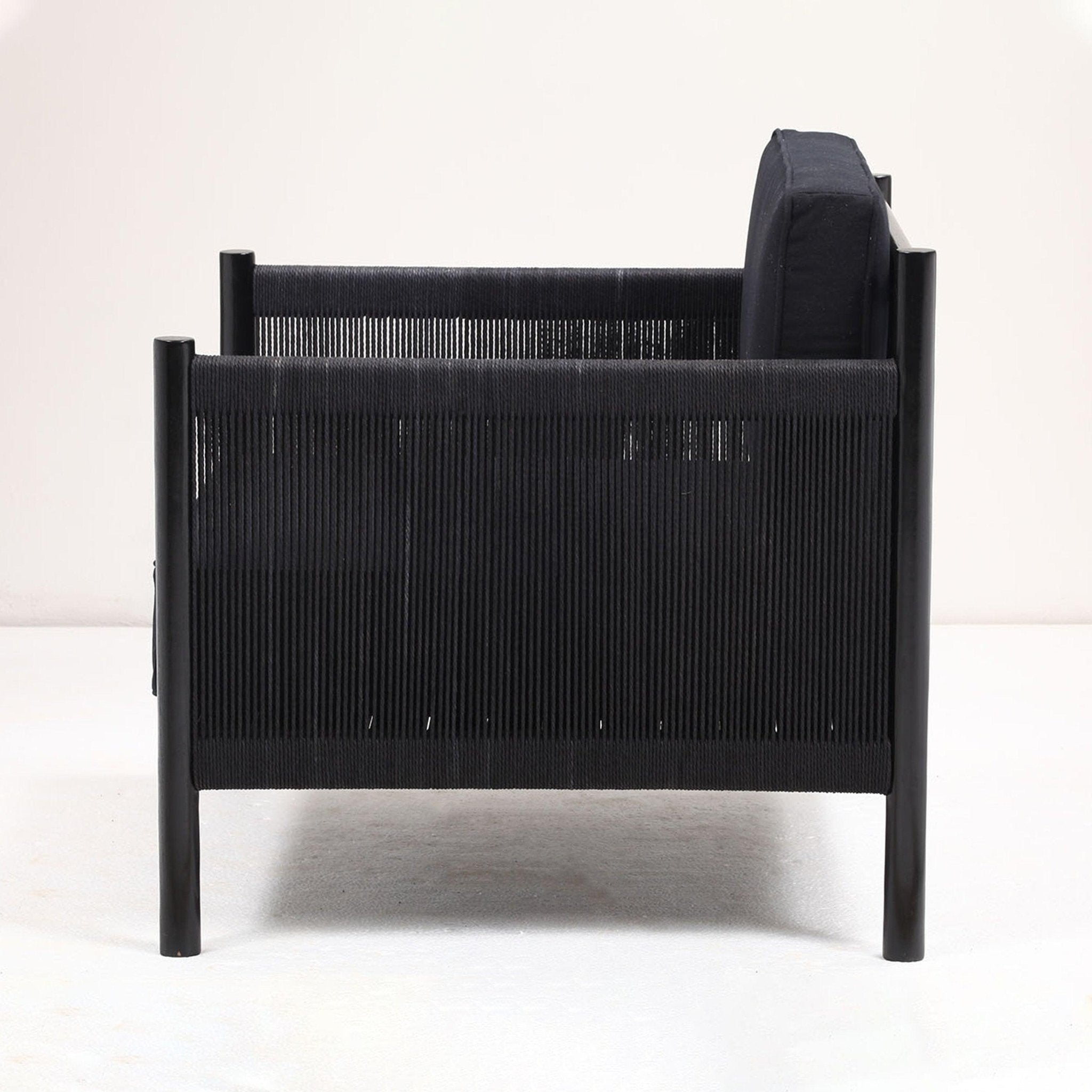 Side view of a modern black lounge chair featuring a solid wood frame, black papercord-wrapped arms and sides, and a cushioned black fabric seat and back.