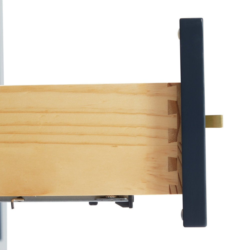 Close-up of a solid wood vanity drawer showing dovetail joinery, pale natural wood interior, dark painted drawer front, satin bronze rectangular pull and metal soft-close slide.