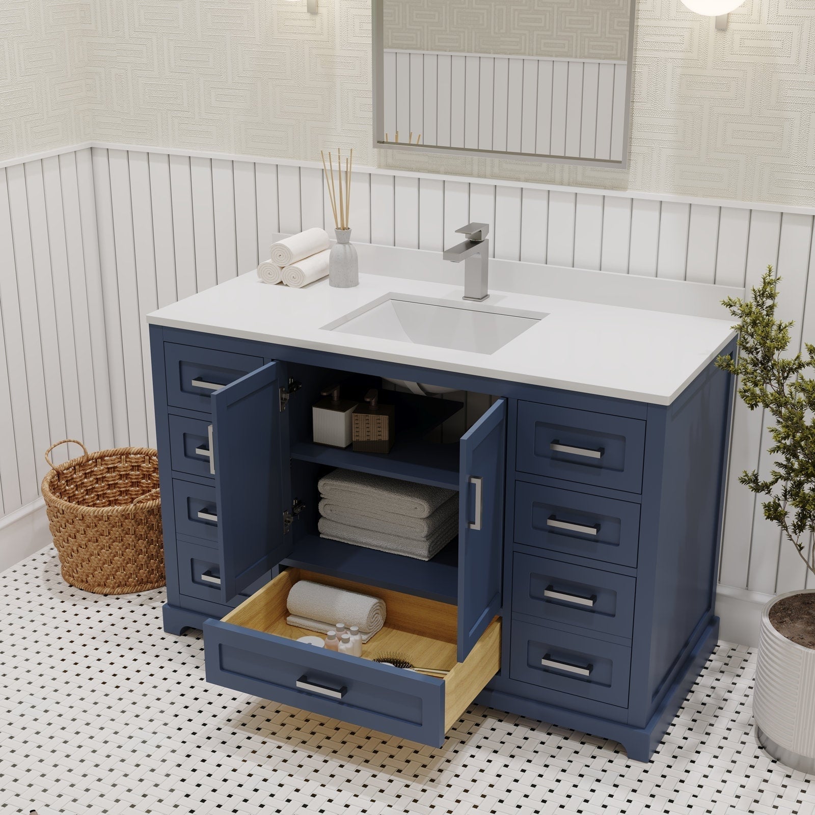 Freestanding 48-inch navy solid wood bathroom vanity with white stone countertop and integrated rectangular ceramic sink, modern brushed-metal faucet and pulls, open center cabinet and wood-lined drawer with towels and toiletries.