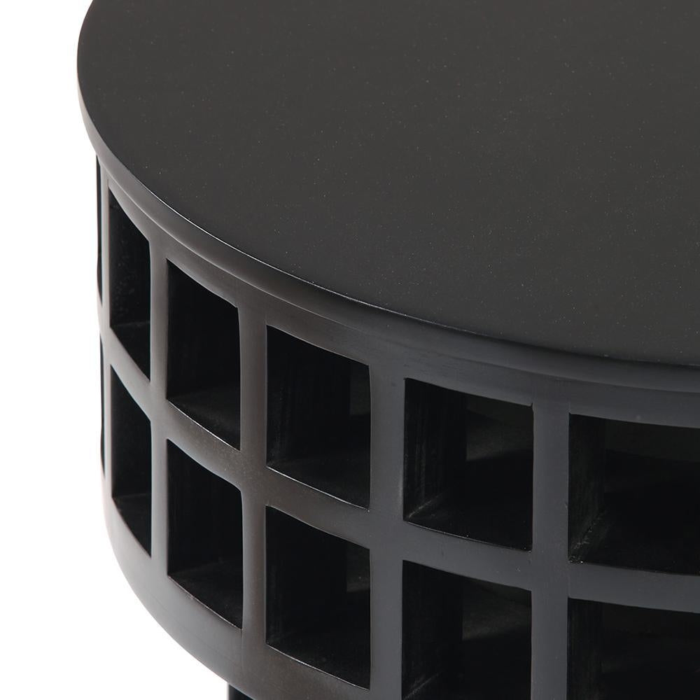 Close-up of a round mahogany-finish black wood side table showing the smooth top and open grid-lattice base with square cutouts, highlighting the modern solid wood construction.