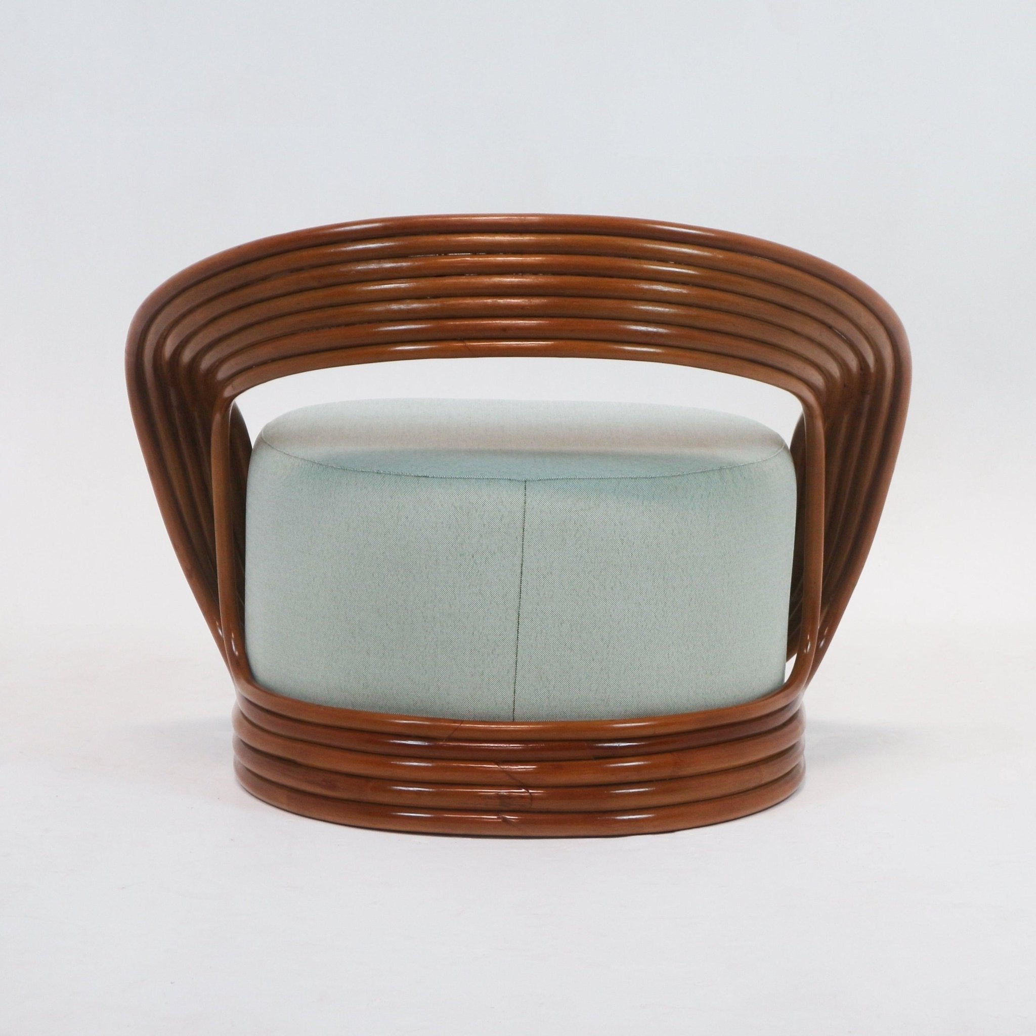 Front view of a mid-century modern lounge chair with mint-green fabric upholstery and a curved brown cane rattan frame that wraps the base and open back.