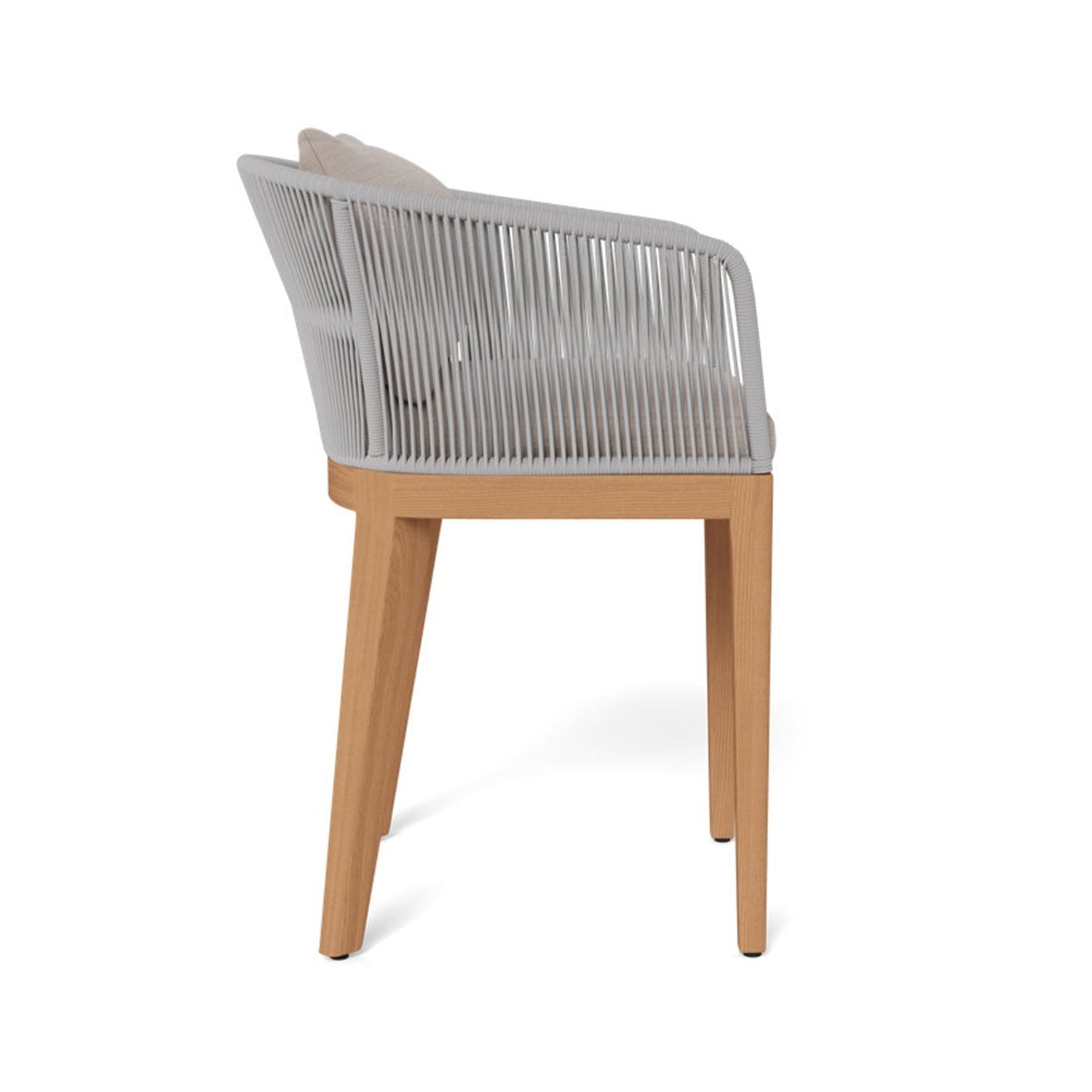 Side view of a coastal-style outdoor bar stool with a teak wood frame, light gray rope-wrapped back and arms, and beige upholstered fabric seat and back cushions.