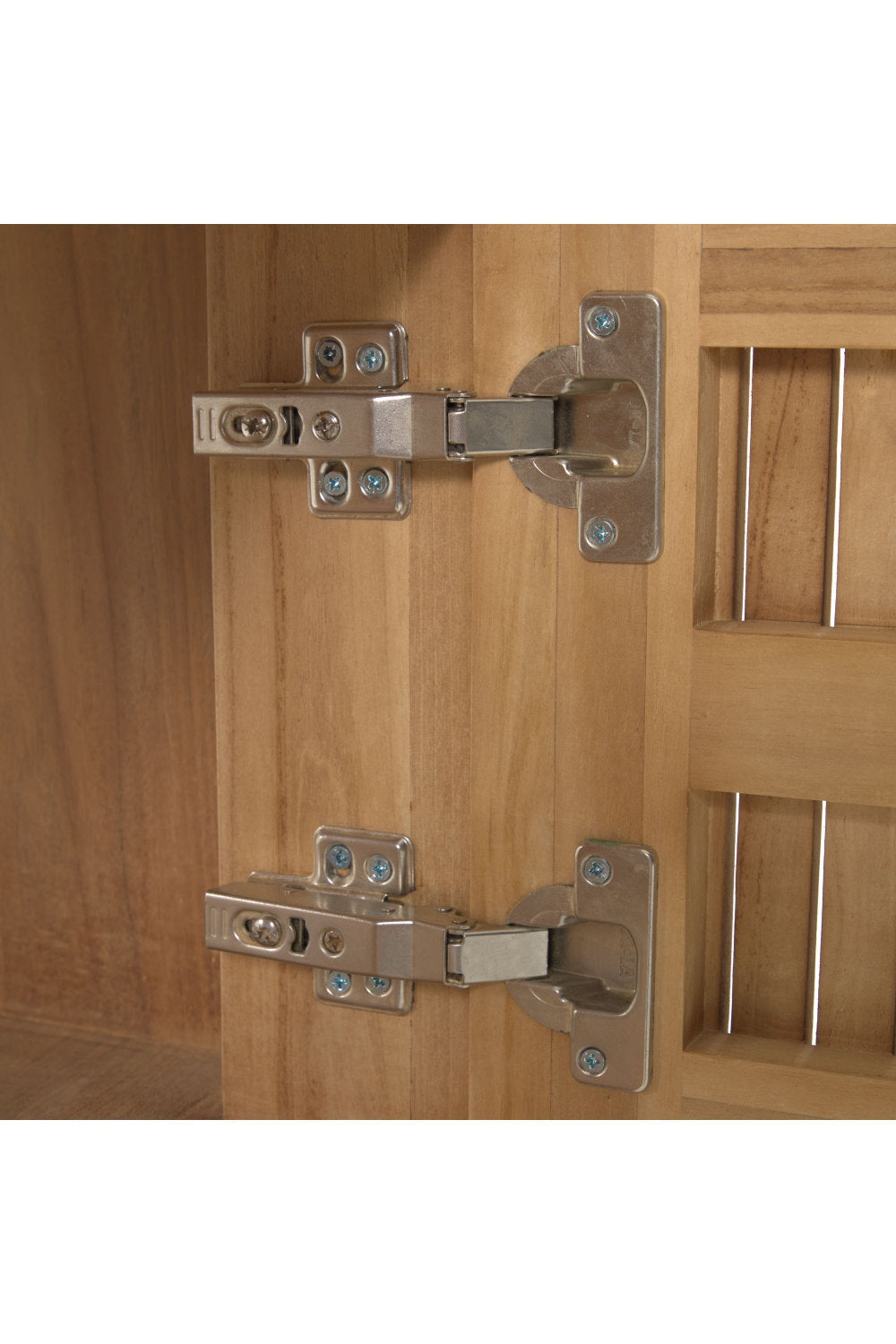 Close-up of two metal concealed cabinet hinges mounted to the natural solid wood interior and slatted vanity door, showing screw plates and hinge arms on a modern bathroom vanity.