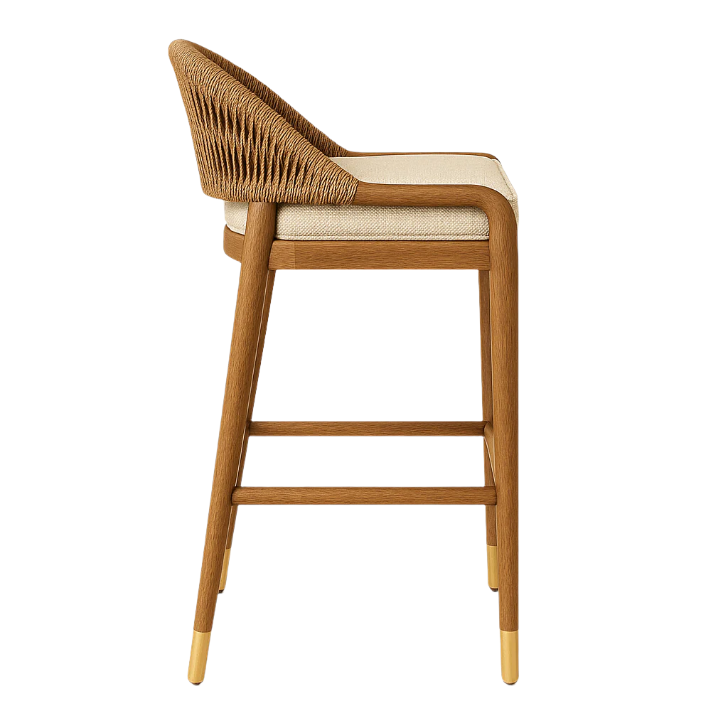 Side view of a coastal-inspired teak-framed counter stool with a woven natural brown rope back, cream upholstered seat cushion, tapered legs and brass-capped feet.