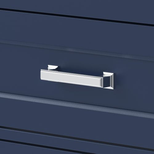 Close-up of a chrome rectangular drawer pull mounted on a deep blue solid wood vanity drawer front with subtle horizontal grooves, reflecting light and reinforcing a glam bathroom aesthetic.
