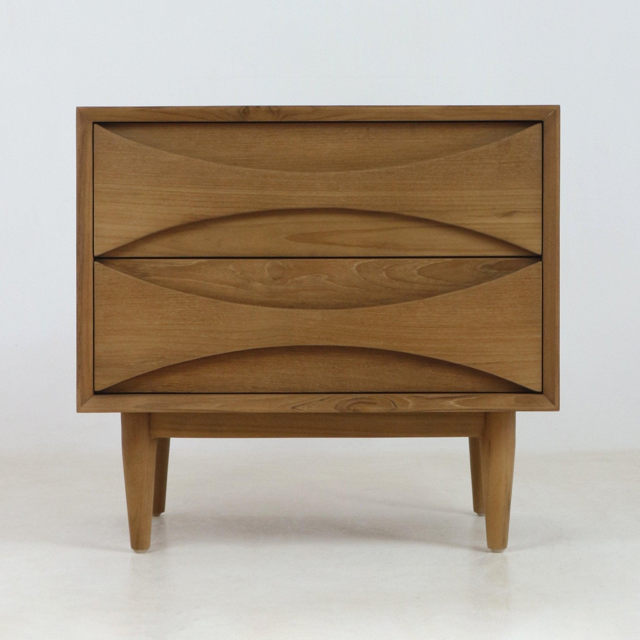 Natural teak solid wood nightstand with two drawers featuring carved recessed pulls, tapered mid-century modern legs and a clean Scandinavian silhouette.