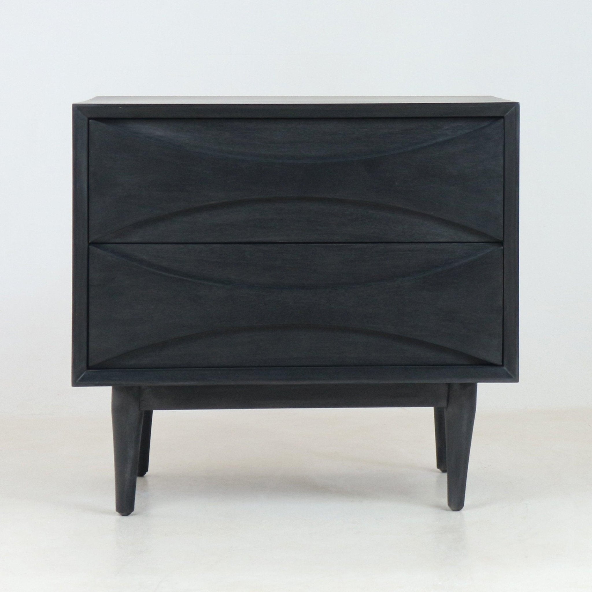 Front view of a mid-century modern solid wood nightstand in smoked black finish, with two sculpted drawers featuring curved recessed fronts and tapered legs on a plain white studio background.