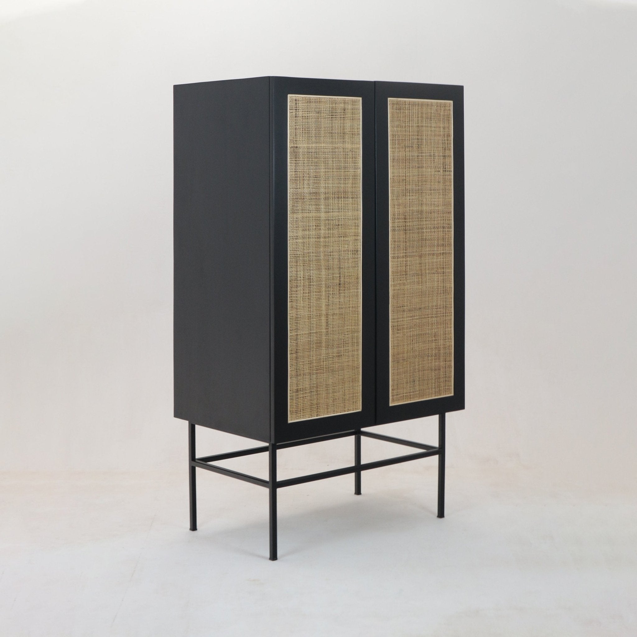 Tall modern black wardrobe with natural woven cane panels on two doors, a solid wood body and slim black metal legs and frame.