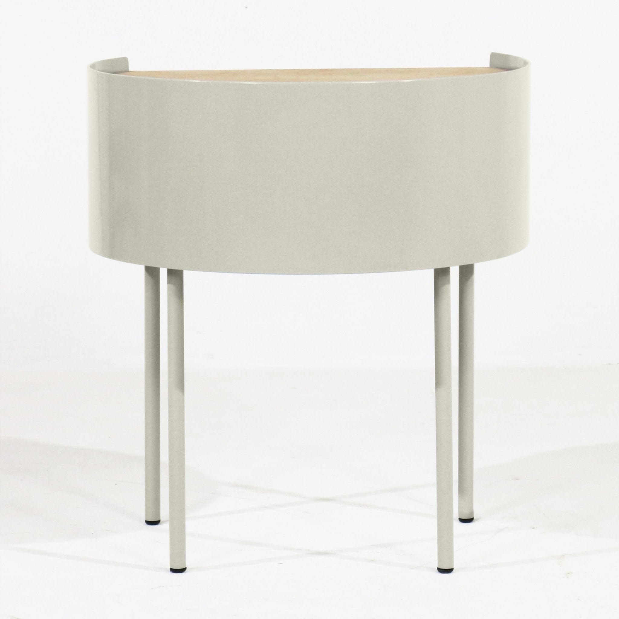 Modern curved nightstand with a light gray steel drum body, white oak top, and four slender steel legs, photographed on a white background.